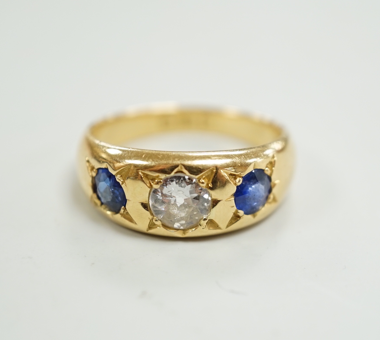 An early 20th century 18ct gold and gypsy set single stone diamond and two stone sapphire set ring, size O, gross weight 6.4 grams.